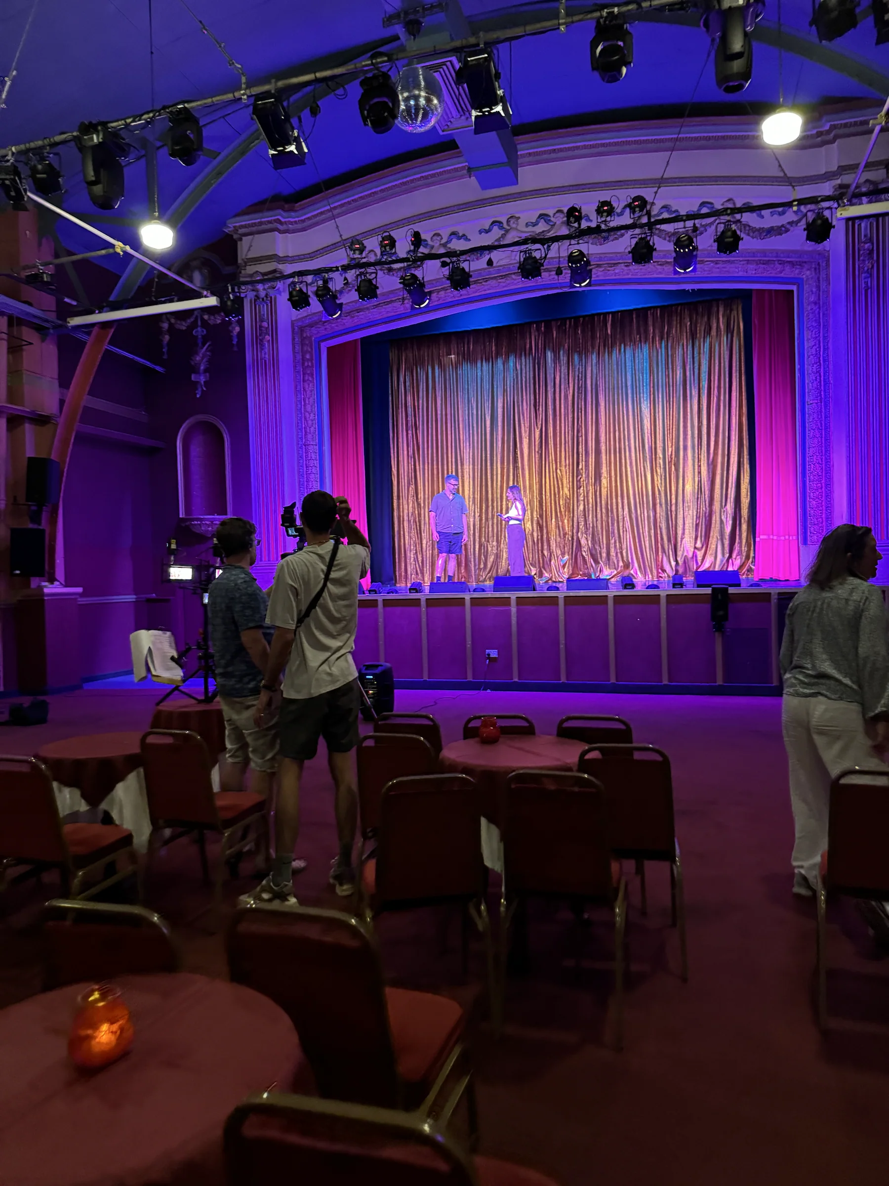 Production crew watching two contributors on the theatre stage