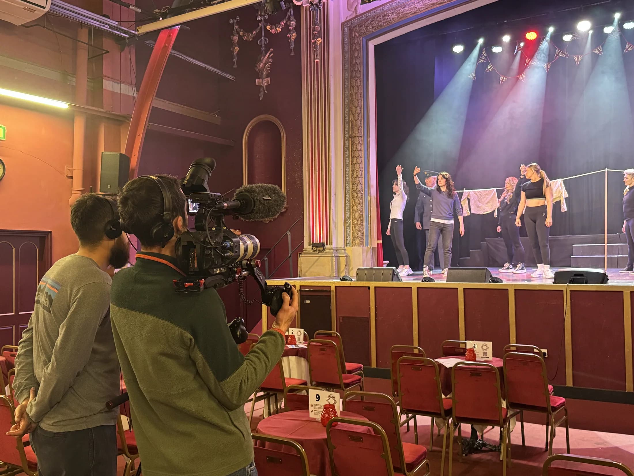 A camera operator filming performers on the Pavilion stage