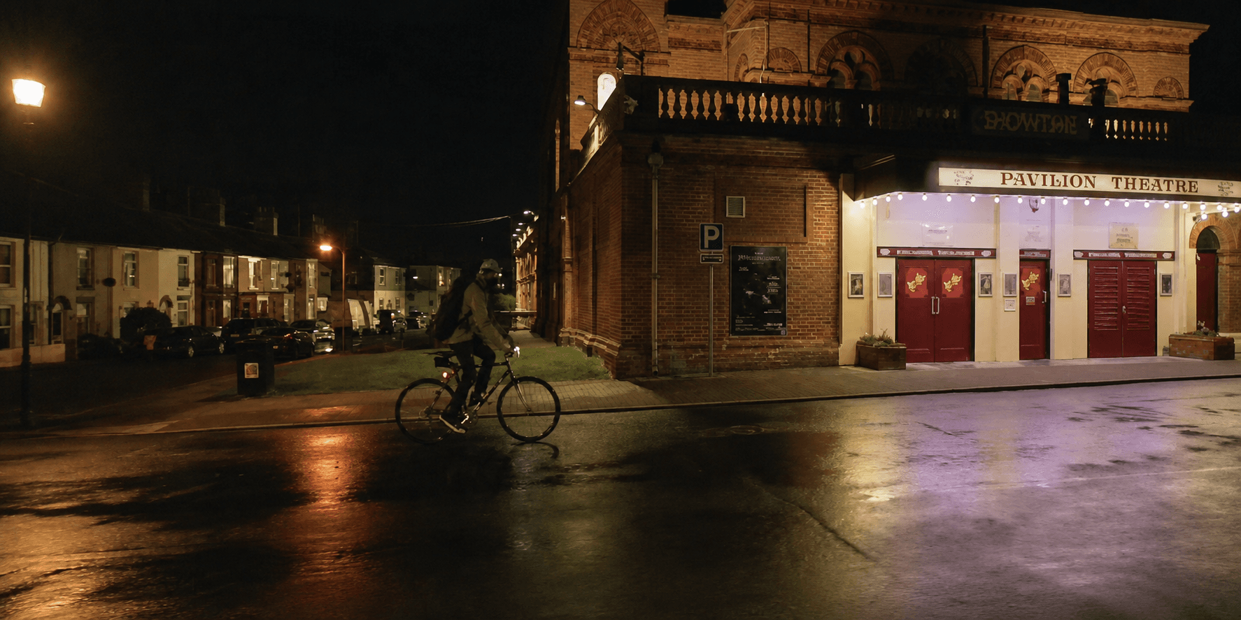 A cyclist passing the illuminated Pavilion Theatre in a scene from Yesterday