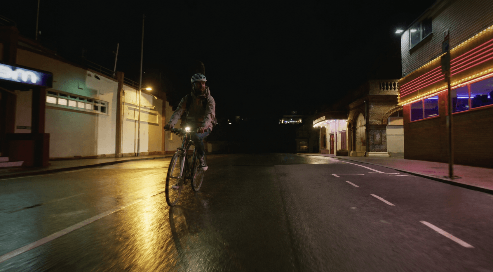 A cyclist riding towards the camera with the Pavilion Theatre behind in Yesterday